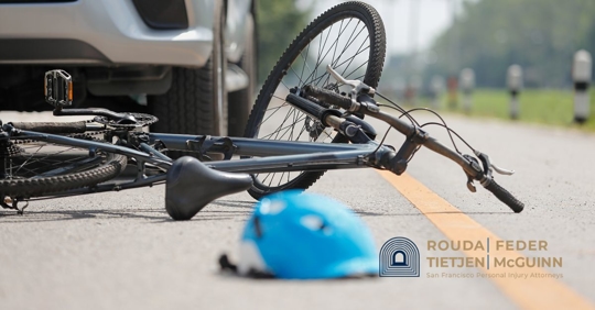 bicycle and helmet laying next to a car.